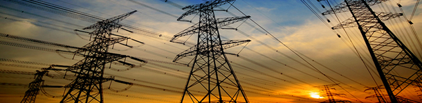 View of electrical power lines with a sun setting in the background.