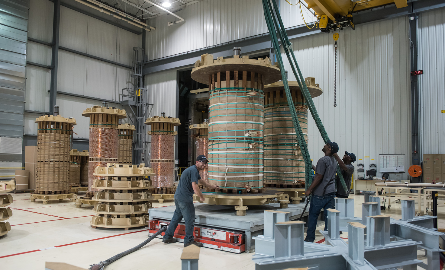 Manufacturing employees winding coils for transformer manufacturing.