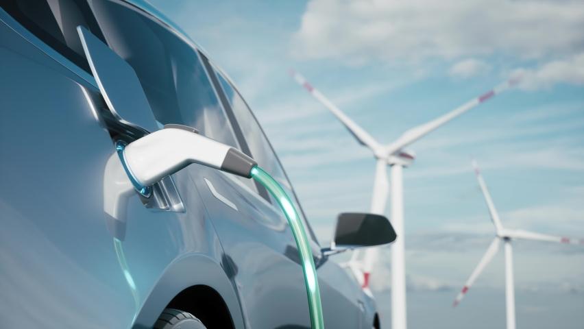 Electric vehicle charging with wind mills in the background.